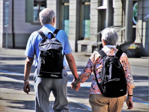 Older couple holding hands while walking through a city street, representing later-life planning and support from Connect Lifetime Mortgages.